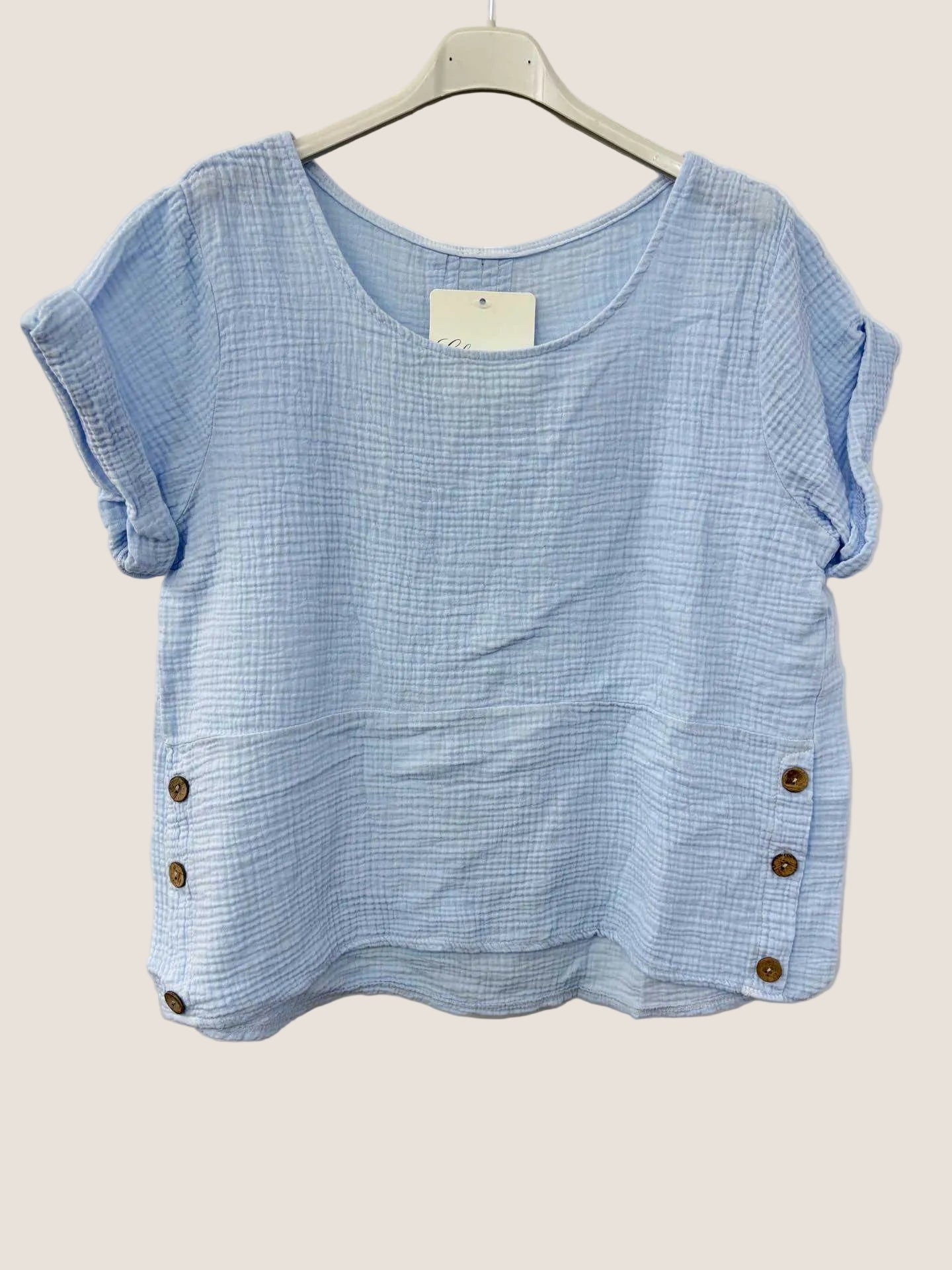 Blue cotton gauze top with button details on a white background