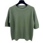 Green sweater on a hanger against a white background