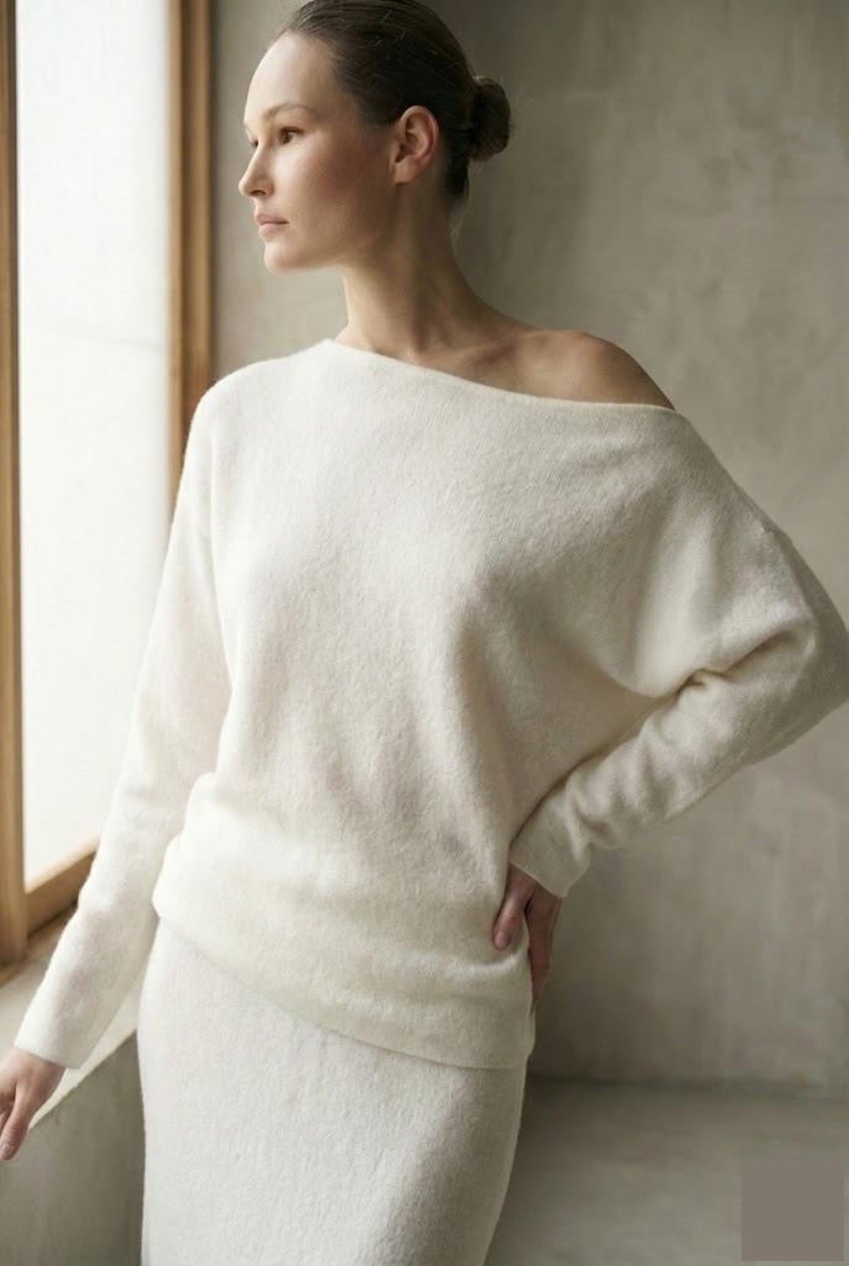 Woman wearing a white off-shoulder sweater.