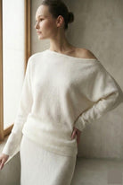 Woman wearing a white off-shoulder sweater.