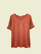 Orange t-shirt on a hanger against a neutral background