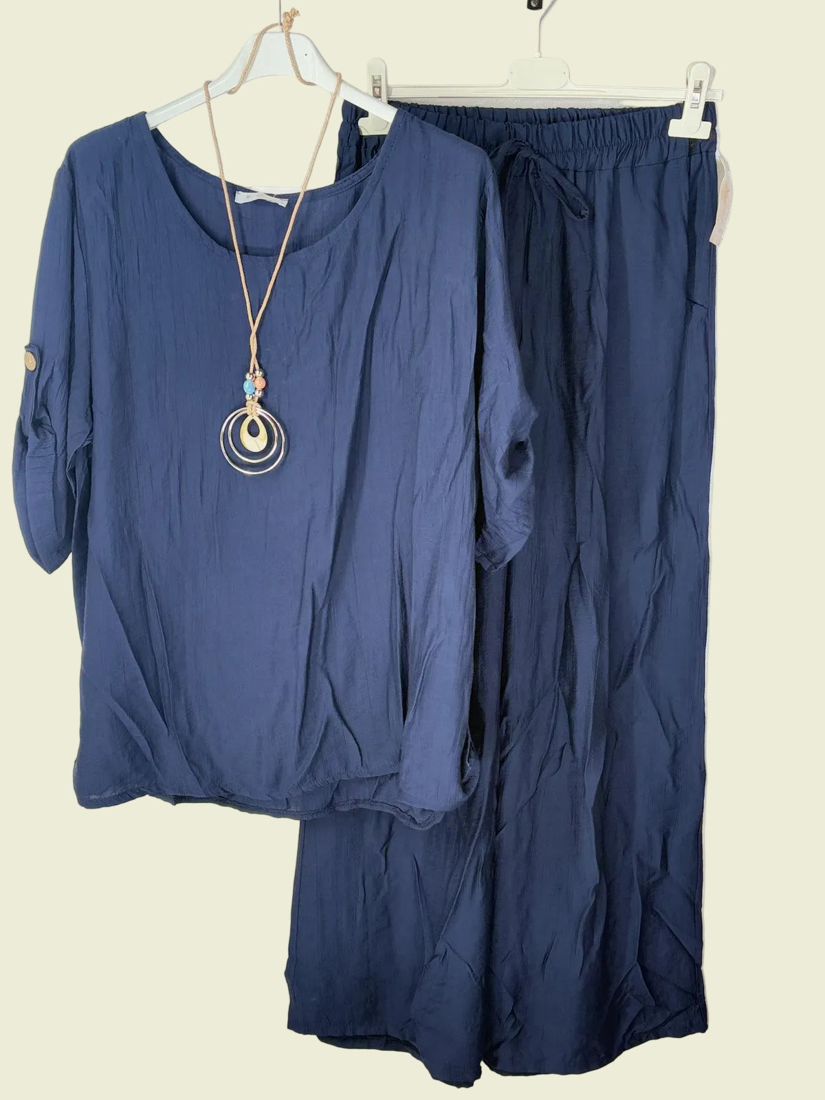 Navy blue outfit with a top and pants on hangers against a white background