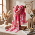 Pink scarf with white patterns on a wooden stand in a cozy room setting.