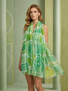 Woman wearing a green and white patterned dress with a matching scarf.