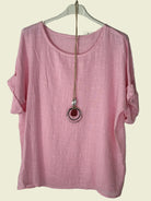 Pink top on a hanger with a necklace 