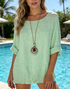 Woman wearing a light green top with a pool in the background