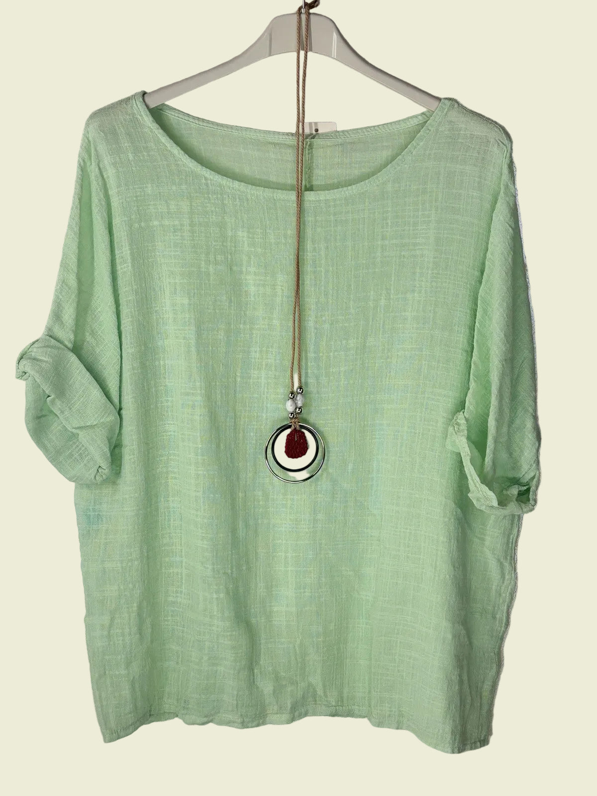Green shirt on a hanger with a necklace 
