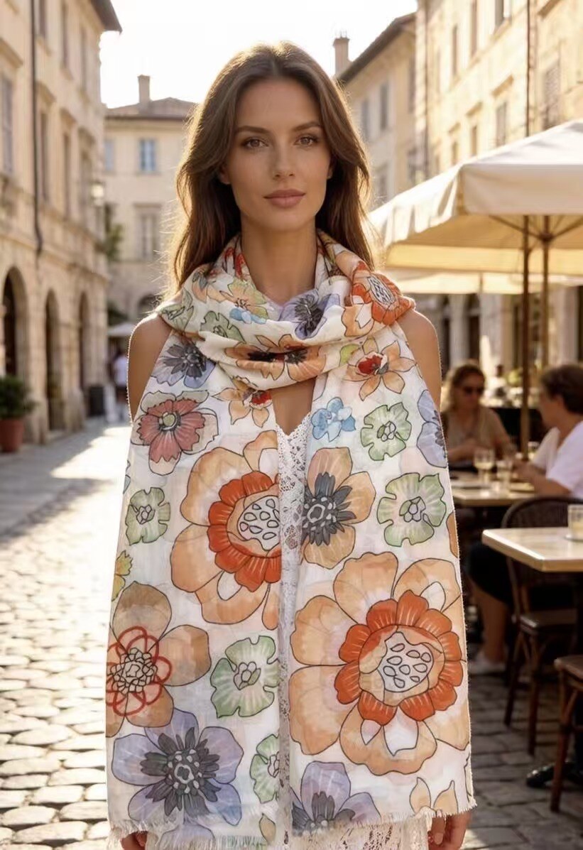 Woman wearing a floral scarf in an outdoor setting with buildings and tables in the background