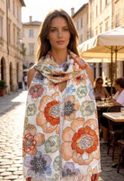 Woman wearing a floral scarf in an outdoor setting with buildings and tables in the background