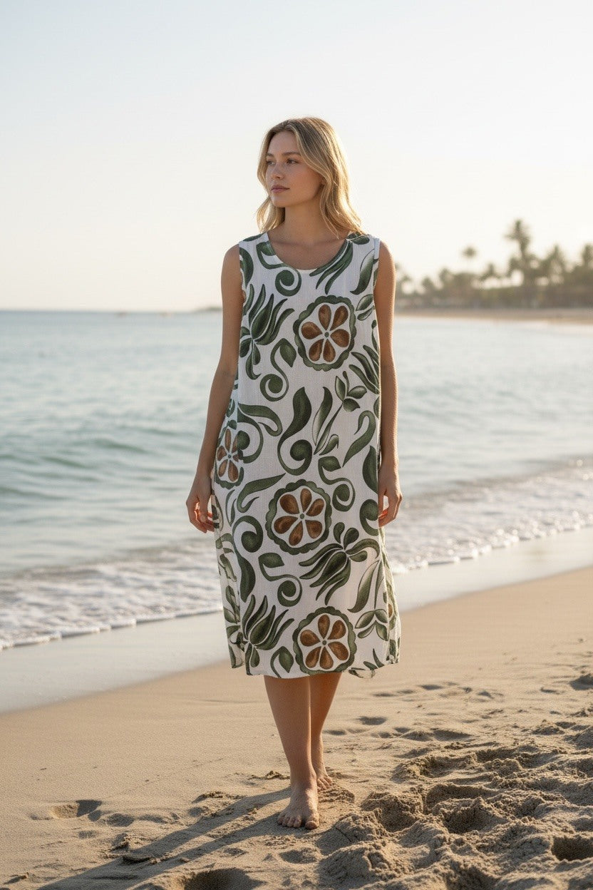 Woman in a floral dress standing on a beach with ocean and sky in the background