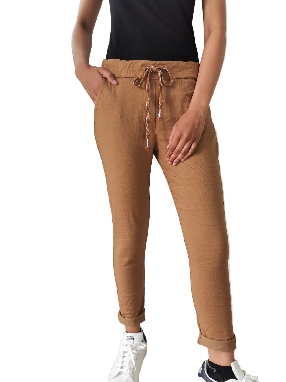 Person wearing brown jogger pants with a white wall and radiator in the background