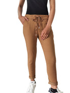 Person wearing brown jogger pants with a white wall and radiator in the background