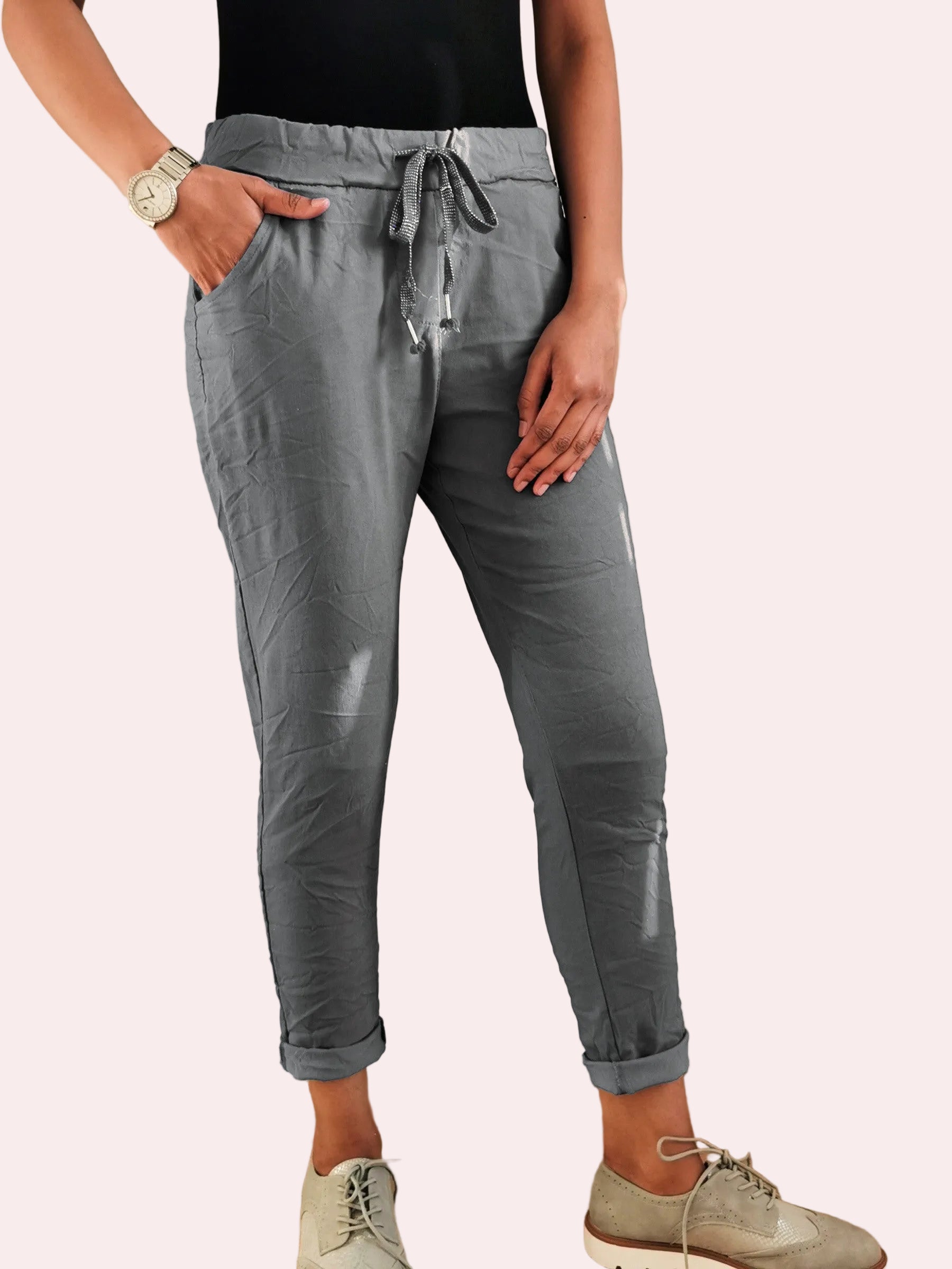 Person wearing gray jogger pants standing indoors with a neutral background