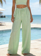 Person wearing light green pants by a pool with ocean view