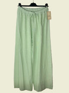 Light green pants on a hanger against a textured gray background