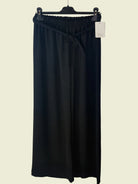 Black pants on a hanger against a textured white background