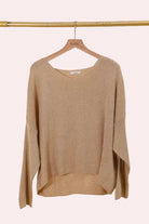 Beige sweater on a hanger against a beige background