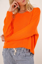 Person wearing an orange sweater with a neutral background