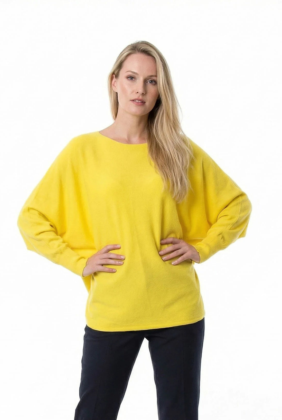 Woman wearing a yellow sweater and black pants on a white background