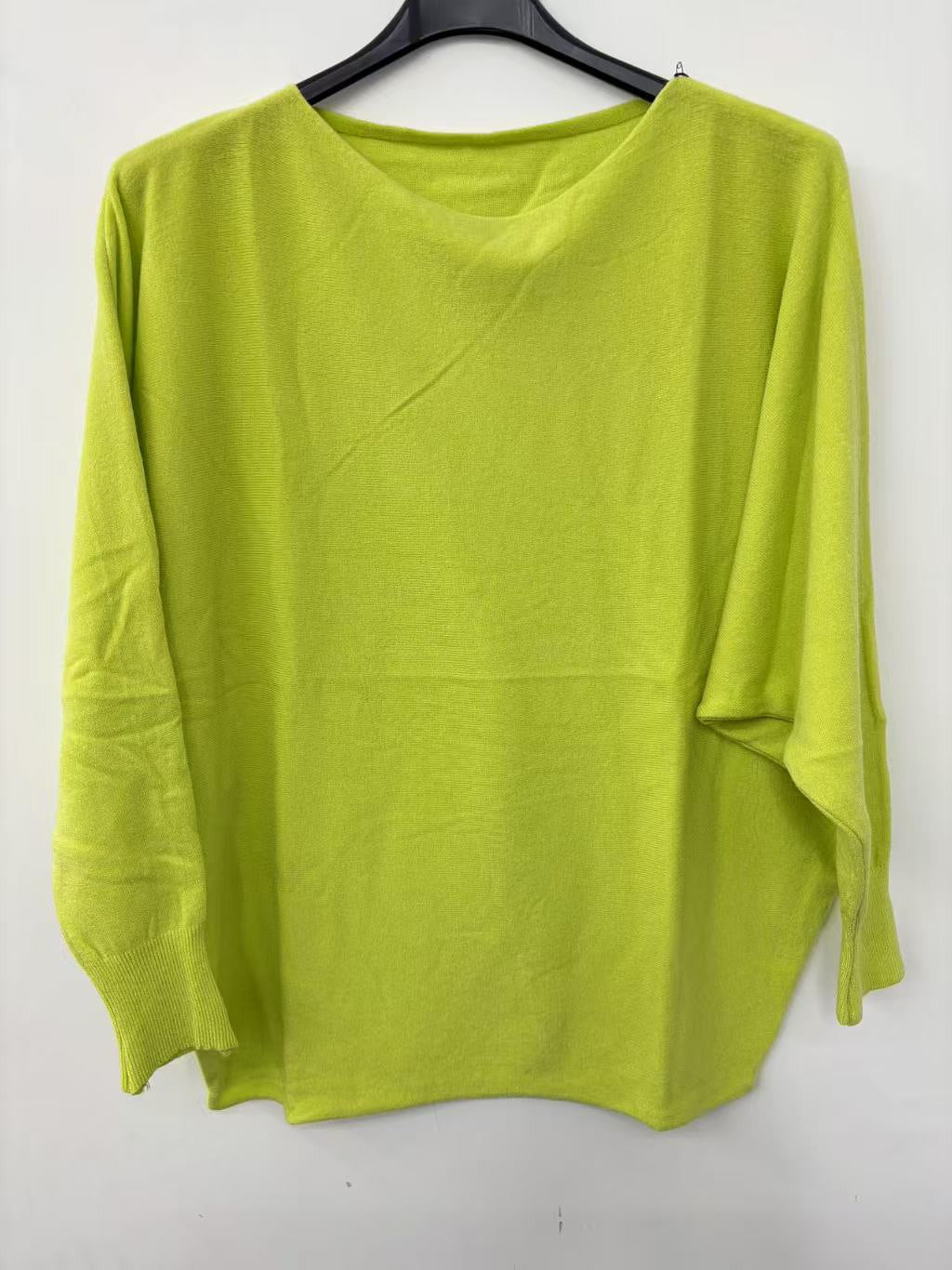 Green sweater on a hanger against a white background