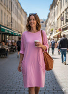 Woman in a pink dress holding a coffee cup on a city street