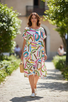 Woman in a colorful dress walking outdoors on a sunny day.