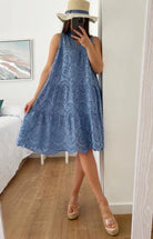 Person wearing a blue lace dress taking a mirror selfie.