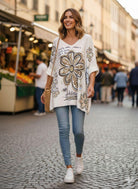 Woman walking on a street wearing a floral-patterned cardigan and jeans.