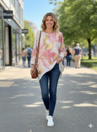 Woman walking on a street wearing a floral sweater and blue jeans.