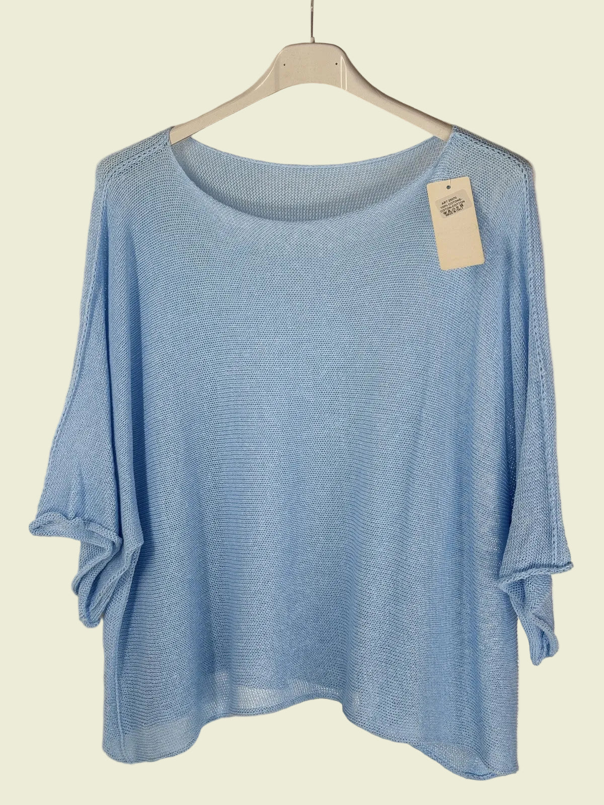 Blue sweater on a hanger with a tag against a neutral background